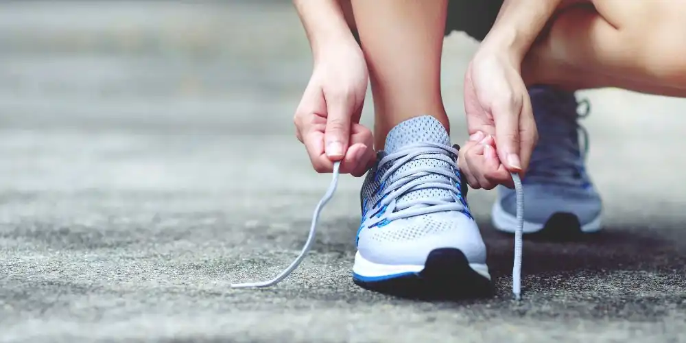 A woman is lacing her lilac running shoes